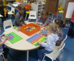 Trois enfants assis autour d'une table ronde faisant des jeux de couleur